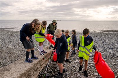 Children wearing high-vis jackets litter picking on Penarth beach